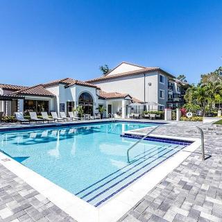 A luxurious outdoor swimming pool next to a residential building on a sunny day.