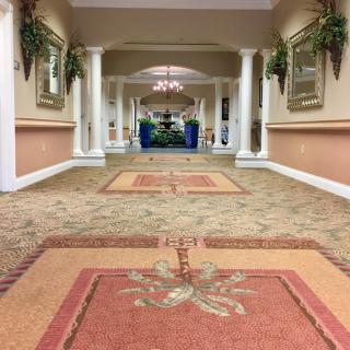 A spacious hallway with carpets and decorative columns.