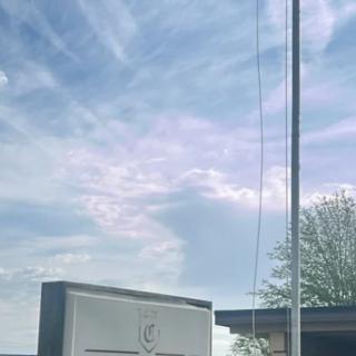 A clear sky with clouds above a flagpole and sign.