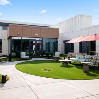 A modern outdoor patio with seating areas and a small lawn on a sunny day.