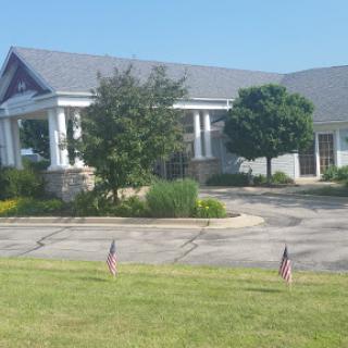 A peaceful view of a well-maintained building surrounded by greenery and small flags.