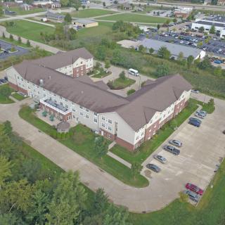 Aerial view of a large building with adjacent parking lot surrounded by greenery.