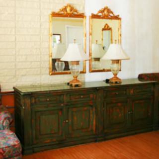 A classic living room setup featuring a dark wooden cabinet topped with lamps, flanked by ornate mirrors.