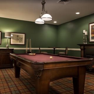 A cozy billiard room with a pool table and classic decor.