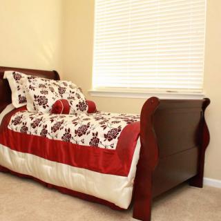 A cozy bedroom with a single bed featuring floral bedding and wooden frame.