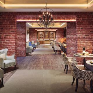 An elegant restaurant interior with brick walls, featuring a cozy dining area and a chandelier.