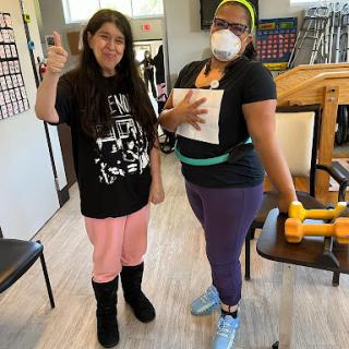 Two individuals engaging in a fitness activity indoors, demonstrating teamwork and support.
