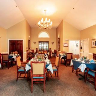 An elegant dining room with neatly arranged tables and chairs under a chandelier.