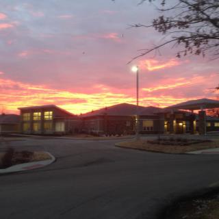A picturesque sunset over a modern building with vibrant colors in the sky.