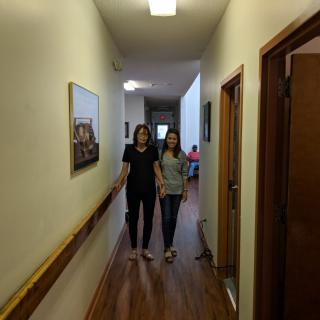 Two people walking down a hallway inside a building.