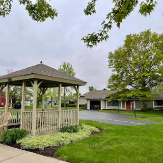 A serene outdoor space featuring a gazebo surrounded by lush greenery and suburban homes.