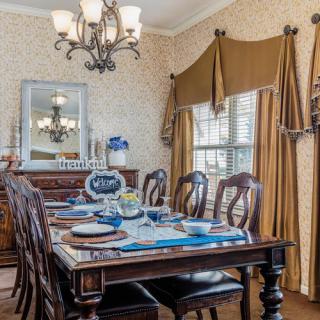 A traditional dining room with a set table, featuring elegant decor and a chandelier.