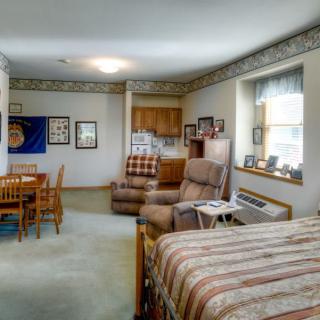 A cozy apartment interior featuring a combined living and sleeping area with a kitchenette and dining table.