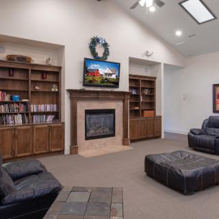 A cozy living room featuring a fireplace, bookshelves, and comfortable seating with a television mounted above the mantel.