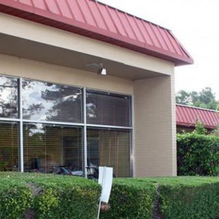 Exterior view of a building with large windows and surrounding bushes.