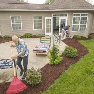 People working on landscaping and mulching in a garden patio area.
