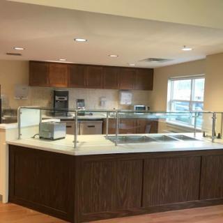 A contemporary kitchen featuring wooden cabinetry and an open design, illuminated by natural light.