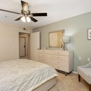 A cozy bedroom featuring a bed, dresser, and a ceiling fan.