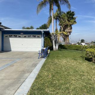 A suburban house with a garage and well-maintained lawn, featuring palm trees.