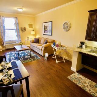 A cozy living room with a sofa, coffee table, and dining area, featuring warm lighting and elegant decor.