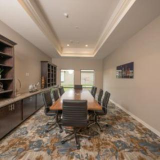 A modern conference room with a long table and chairs, featuring stylish office decor.