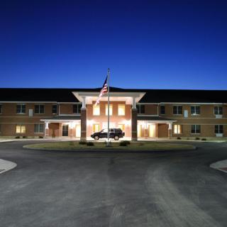 A well-lit building entrance at night with a flag in front.