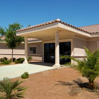 A single-story building entrance with columns and landscaping on a sunny day.