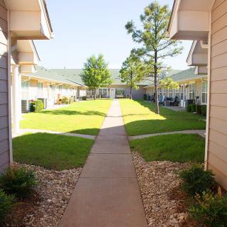 A sunny day at an apartment complex with a pathway and well-maintained lawns.