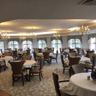 A spacious and elegantly decorated dining room with tables and chairs set for guests.