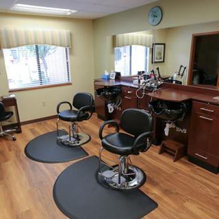 An interior view of an empty hair salon with two barber chairs and mirrors.