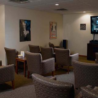 A cozy waiting room with arranged chairs, a television, and wall posters.