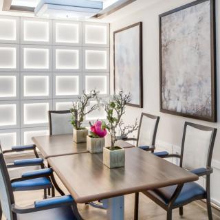 A modern dining room with a wooden table, upholstered chairs, and contemporary artwork on the walls.