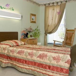A cozy bedroom with a single bed, rocking chair, and floral decorations.