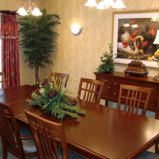 A beautifully decorated dining room with a long wooden table and chairs, complemented by plants and artwork.