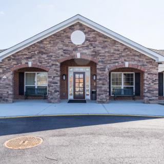 A brick building with a symmetrical design and a central entrance flanked by large windows.