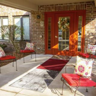 A cozy patio with red-accented seating and a stylish entrance.