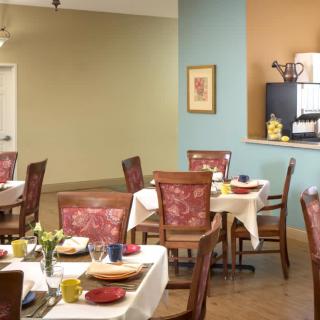 A cozy dining area with neatly set tables and comfortable chairs, featuring a warm interior design.