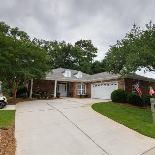 A suburban house with a neatly maintained lawn and driveway, displaying American flags on a cloudy day.
