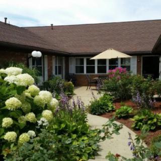 A beautiful garden with a variety of flowers and a pathway leading to a house.