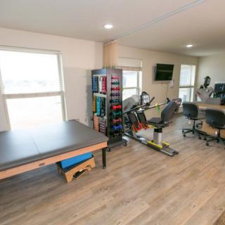 A well-equipped gym with a stationary bike, weights, and exercise mats.