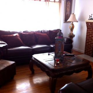 A cozy living room with a leather sofa, wooden coffee table, and a brick fireplace.