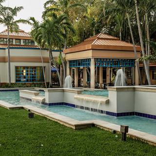 A luxurious tropical resort featuring elegant architecture and a serene fountain surrounded by lush greenery.