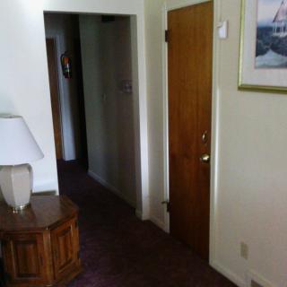 A cozy hallway with a wooden door, side table, and decorative painting.