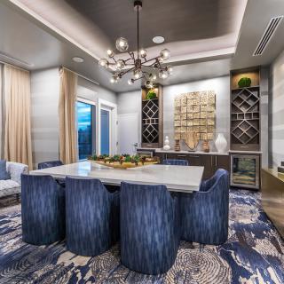 A modern dining room with blue chairs, a sleek chandelier, and stylish decor.