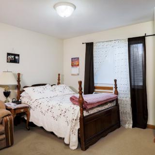A cozy bedroom with a wooden bed, nightstand, and window with curtains.