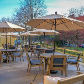 A charming outdoor patio with tables, chairs, and large umbrellas on a sunny day.