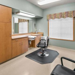 An empty hair salon with a barber chair and mirror.
