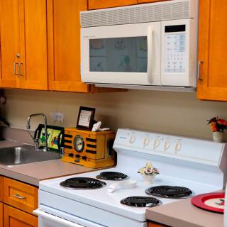A cozy kitchen with wooden cabinets, featuring a stove, microwave, and sink.