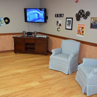 A cozy living room setup featuring two blue chairs, a television, and decorative wall art.