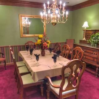 A traditional dining room with elegant decor, featuring a chandelier and a set table.
